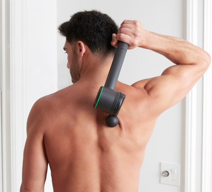 Man massaging his back with Conair Myo-Therapy oscillating percussion massager.