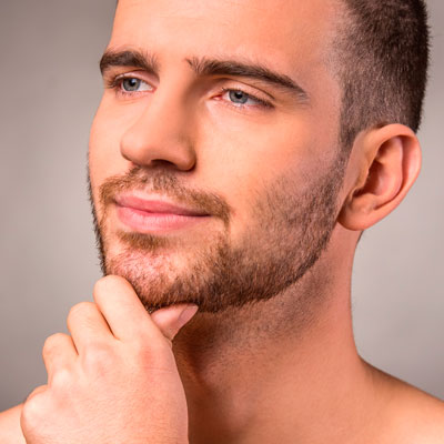 Man looking in the mirror at beard stubble.