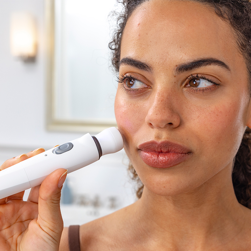 Woman applying rotary shaver to face