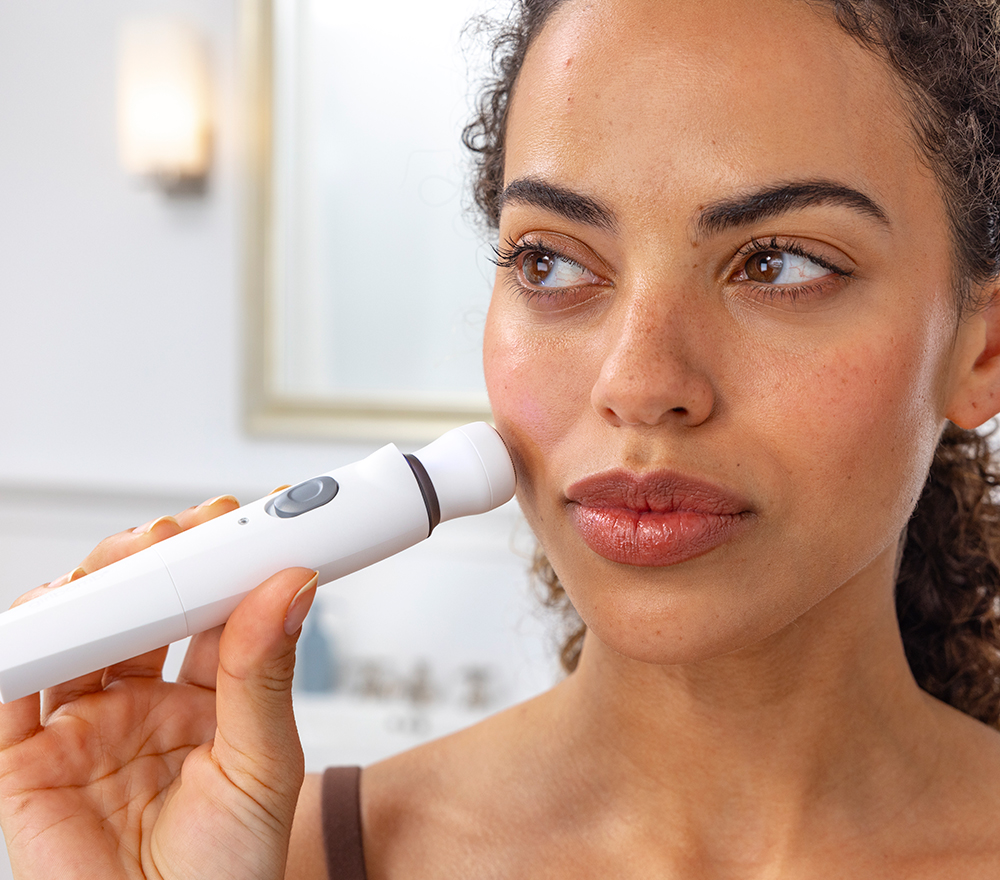 Woman applying rotary shaver to face